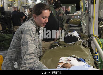 U.S. Air Force Capt. (Dr.) Hannah Gale, pediatrician, San Antonio Military Medical Center Burn Team, consoles a patient during an airlift aeromedical evacuation mission from Guatemala to Galveston, Texas, June 6, 2018. A U.S. Air Force C-17 Globemaster III from the Mississippi Air National Guard's 172nd Airlift Wing transported six injured children and their guardians to Galveston, Texas, for medical treatment at Shriners Hospital for Children. A joint medical team from the Mississippi Air National Guard's 183rd Air Evacuation Squadron and Joint Base San Antonio, Texas, provided en route medic Stock Photo