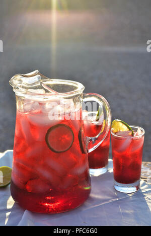 red colorful hibiscus flower iced tea cold drink in glasses and pitcher Stock Photo