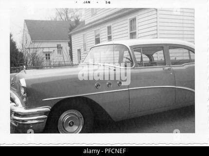Black and white photograph, showing a close-up, partial profile view of a two-tone, hardtop Chevrolet Bel Air, parked in a driveway, with part of a small house visible in the background, likely photographed in Ohio, 1956. ()