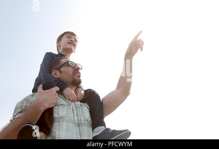little son sits on his father's shoulders Stock Photo