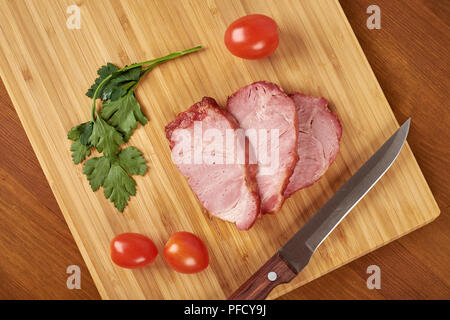 Cooked sliced pork barbecue steak on wooden cutting board. Stock Photo