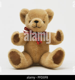 Teddy bear wearing a red bow tie sitting on red floor, wooden wall ...