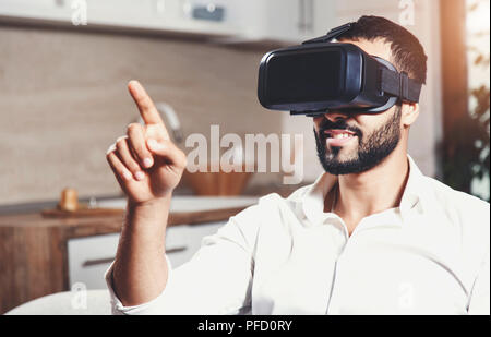 Handsome bearded man using virtual reality goggles in the modern flat Stock Photo