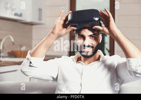 Multicultural bearded man using virtual reality goggles in the modern flat Stock Photo