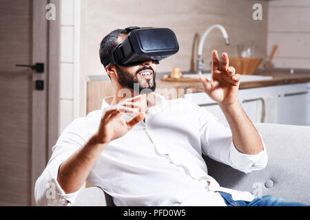 Multicultural bearded man using virtual reality goggles in the modern flat Stock Photo