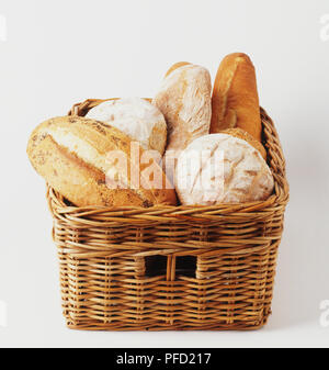 Assorted bread loaves in a woven straw basket. Stock Photo