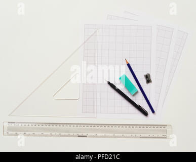 Graph paper, pen, eraser, pencil, pencil sharpener and rulers, view from above. Stock Photo