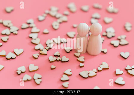 the concept of a loving couple. A happy couple in love. Two wooden figures and hearts on a pink background Stock Photo