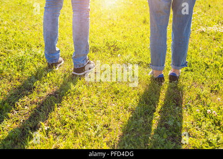 Travel together concept - stylish couple legs on sunny grass in meadow in summer Stock Photo