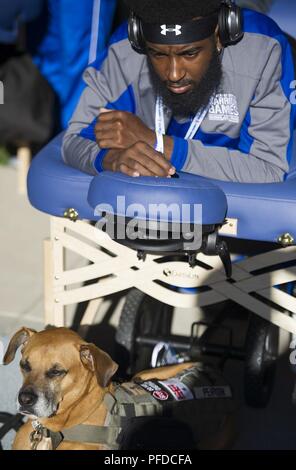Team Air Force Veteran Anthony Pearson receives medical treatment during the track & field events, June 2, 2018, at the DoD Warrior Games while his service dog, Rocky, waits by his side. The Warrior Games, taking place June 1-9, 2018, at the U.S. Air Force Academy in Colorado, are a Paralympic-style competition for wounded, and injured service members from all U.S. branches of service and this year include teams from the United Kingdom Armed Forces, Australian Defence Force and Canadian Armed Forces. Stock Photo
