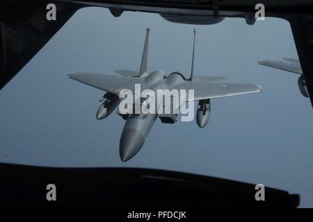 A U.S. Air Force F-15C Eagle assigned to the 18th Wing at Kadena Air Base, Japan, follows a KC-10 Extender from 6th Air Refueling Squadron, Travis Air Force Base, Calif., June 2, 2018 after refueling. The KC-10 refueled two F-15s a total of 16 times, offloading a total of 78,400 pounds of fuel over a distance covering nearly 2,300 miles on a mission in the Pacific region. Stock Photo