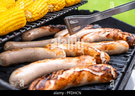 Freshly cooked sausages on a grill with corn close-up. Background of sausages made with charcoal. Stock Photo