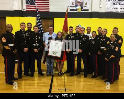 Left to right, Sgt. Maj. Cortez L. Brown, Maj. Jonathan W. Landers, Gunnery Sgt. Isaac M. Ishak, Pfc. Gavin G. Northcutt, Marty Northcutt, Tori Northcutt, Col. Jeffrey C. Smitherman, Staff Sgt. Brian D. Raney, Capt. Kyle R. Kuhn, retired Master Sgt. Bud Schell, Capt. Asia Pastor, Gunnery Sgt. Nathan D. Mitchaner, Staff Sgt. Jon P. Slayton, Sgt. Maj. Rena M. Bruno and Staff Sgt. James B. Benham stand with Hunter A. Northcutt’s Honorary Marine award at Pelham Elementary School, Pelham, Tennessee, June 13, 2018. Only the Commandant of the Marine Corps can officially designate an individual as an  Stock Photo