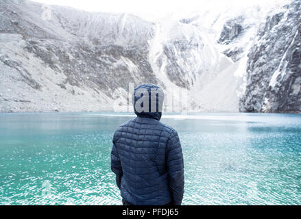 Man from behind looking at the turquoise lagoon in Huascaran National Park. Laguna 69, Cordillera Blanca mountain range, Ancash Region, Peru. Jul 2018 Stock Photo