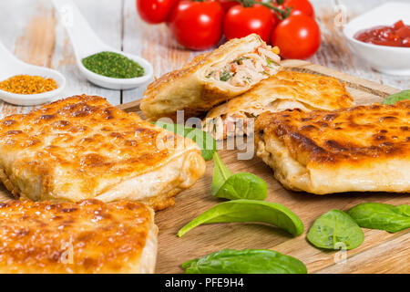 fried Pita or flatbread Stuffed with chicken meat, Cucumber, coleslaw, tomato ,spinach, dill and sauce on chopping board with ketchup, tomatoes and sp Stock Photo