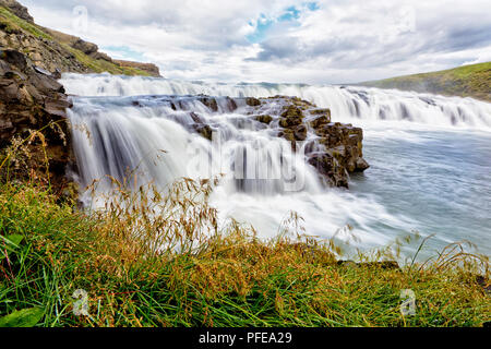 GULLFOSS, ICELAND. 3RD AUGUST 2016: Long exposure of first set of waterfalls in Gullfoss with green reed in the foreground. Stock Photo
