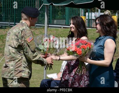 U.S. Army Sgt. Hunter Bishop, Landstuhl Regional Medical Center non-commissioned officer of the year, presents flowers to Miss Abby Charpentier (middle) at her father's relinquishment of responsibility on May 30, 2018 at Landstuhl/Germany Stock Photo