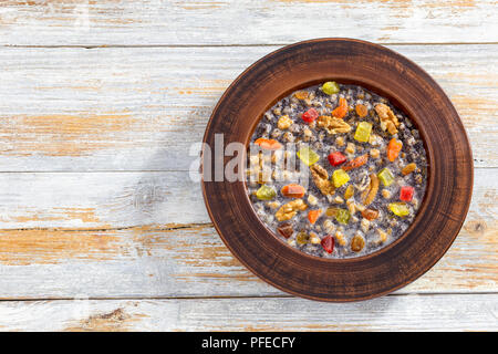 Sweet wheat kutia with nuts, poppy seeds, dried fruits. succade and honey in clay bowl on wooden planks.Traditional Christmas dish in russia and ukrai Stock Photo