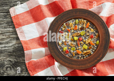 kutya or Sweet Wheat Berry Pudding, traditional Christmas dish in clay rustic bowl on table cloth on dark wooden table, view from above Stock Photo