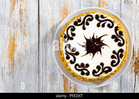 delicious sponge cake with honey and prunes, layered with whipped heavy cream,  decorated with chocolate  frosting, view from above Stock Photo