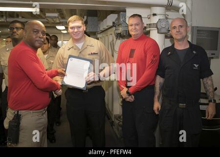 ATLANTIC OCEAN (June 4, 2018) -- Aviation Ordnanceman 2nd Class Zachary Tuttle, from Kewanee, Illinois, assigned to USS Gerald R. Ford’s (CVN 78) weapons department, receives his frocking letter from Cmdr. Travis Davis, Ford's gun boss, during a promotion ceremony in the ship's weapons handling area. Ford is currently underway conducting test and evaluation operations. Stock Photo