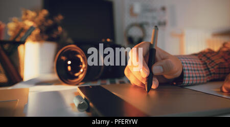 Graphic designer working on digital tablet. Camera on desk in background. Photographer working at office. Stock Photo