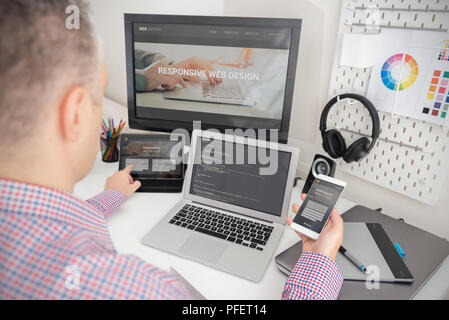 Designer working on responsive web design project. Web developer and programmer working in office with modern devices on desk Stock Photo
