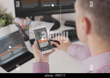 Designer working on responsive web design project. Web developer and programmer working in office with modern devices on desk Stock Photo