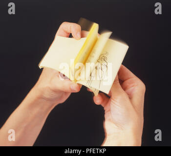 Hands holding cartoon flick book, close up. Stock Photo