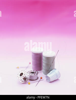 Two cotton thread reels, two bobbins, sewing needles and darts and a thimble Stock Photo