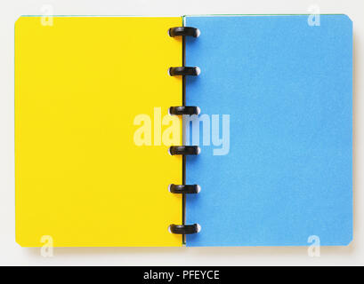 Open spiral-bound notebook, showing a yellow and a blue page Stock Photo