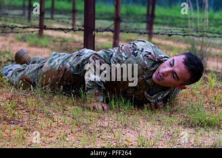 U.S. Army Reserve Spc. Nicolas Cholula, a combat documentation production specialist from Oxnard, California, with the 311th Signal Command (Theater Support Unit) performs a low crawl on obstacle four of the Fort Bragg Air Assault School obstacle course. Touching the barbed wire with any part of their body during this lane results in disqualification, requiring the competitor to be returned to the beginning of the lane to try again or continue with a loss of points.  Thirty-six warriors continue to vie for the title of United States Army Reserve Best Warrior during the grueling multifaceted co Stock Photo