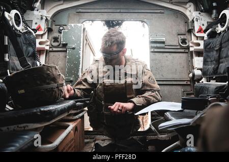 1st Lt. Caleb Grow, Grand Rapids, Michigan native, platoon leader with 1st Squadron, 2nd Cavalry Regiment, reads maps inside of an Interim Armored Vehicle 'Stryker” during a multinational quick response exercise, Bull Run 5.5, with Battle Group Poland at Bemowo Piskie Training Area, Poland on June 11, 2018 as part of Saber Strike 18. This year's exercise, which runs from June 3-15, tests allies and partners from 19 countries on their ability work together to deter aggression in the region and improve each unit's ability to perform their designated mission. Stock Photo
