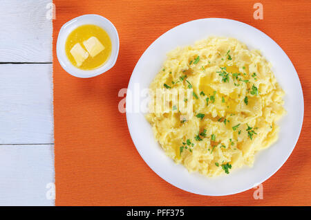 delicious hot mashed potato with melted butter and finely chopped parsley on plate on table mat, view from above Stock Photo