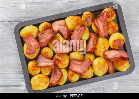 Delicious new potato baked in oven with roasted Pork Ribs in dish on white wooden boards, view from above Stock Photo