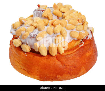 delicious freshly baked homemade cinnamon roll topped with peanuts, isolated on white background, close-up Stock Photo