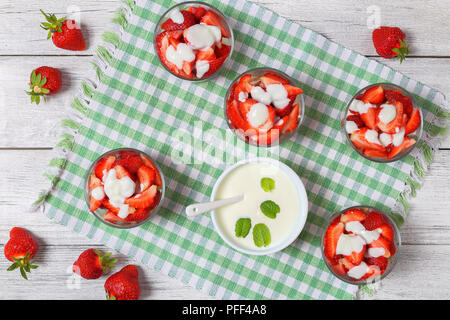 fresh ripe organic strawberries cut in slices in glass jars drizzle with homemade natural low fat yogurt, healthy breakfast, view from above Stock Photo