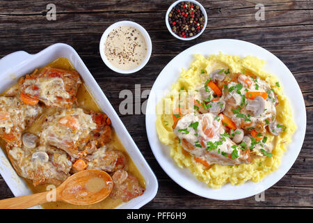 delicious pieces of Rabbit braised in sour cream with mushrooms and carrots served with mashed potatoes sprinkled with parsley on white plate on dark 