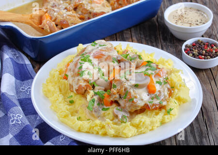 delicious pieces of Rabbit braised in sour cream sauce with mushrooms and carrots served with mashed potatoes sprinkled with parsley on white plate on Stock Photo