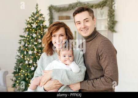 Parents and baby near Christmas tree Stock Photo