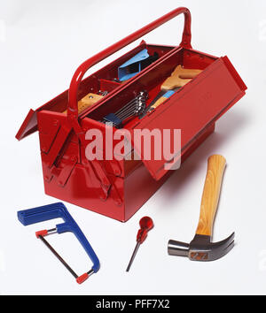 Hammer, screwdriver and saw in front of red tool box with lid open, elevated view Stock Photo