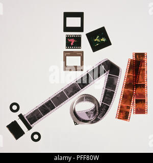 Roll of black and white negative film, strips of coloured negative film, coloured slides in and out of cases, view from above. Stock Photo