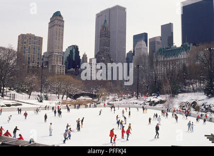 USA, New York, Manhattan, Central Park, ice skaters on Wollman ice rink, skyscrapers in background. Stock Photo