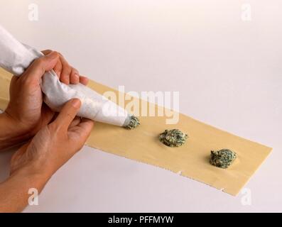 Making ravioli, piping spinach and ricotta filling onto rolled out dough Stock Photo