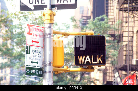 USA, New York City, signs attached to pole, including 'Walk' signal and 'One Way' sign Stock Photo