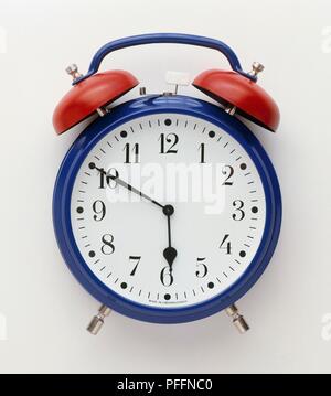 A blue and red alarm clock with bells, front view Stock Photo