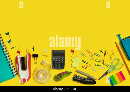 multiple school and office suplies and gadget lying on a yellow background Stock Photo
