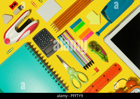 different school and office stationary and gadgets lying on a yellow surface. free space for advertising text Stock Photo