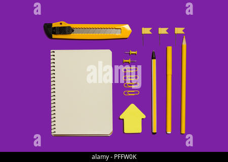 opened notebook, colorful stickers, paper clips, pencil, pen and stationary knife lying on a purple surface. concept of educational chancery Stock Photo