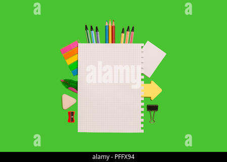 different office supplies surrounding a white sheet of paper lying on a green surface. concept of educational chancery. free space for advertising tex Stock Photo